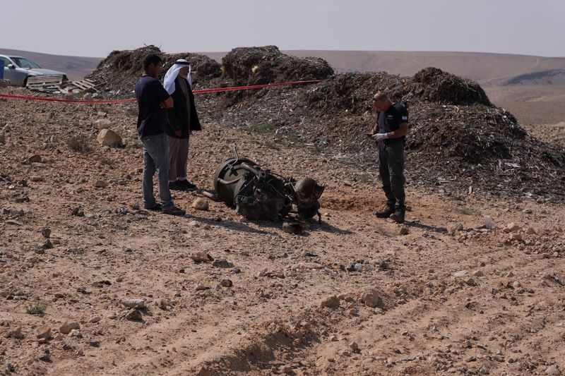 © Reuters. A police officer and residents inspect the remains of a rocket booster that, according to Israeli authorities critically injured a 7-year-old girl, after Iran launched drones and missiles towards Israel, near Arad, Israel, April 14, 2024. REUTERS/Christophe van der Perre