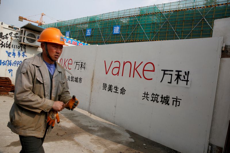 © Reuters. FILE PHOTO: A person walks past by a gate with a sign of Vanke at a construction site in Shanghai, China, March 21, 2017. REUTERS/Aly Song/File Photo
