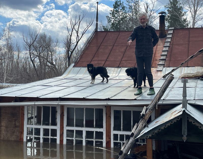 &copy; Reuters. Artist Nikolai Kryuchkov stands on the roof of his flooded house in Orenburg, Russia, April 13, 2024. REUTERS/Alexander Reshetnikov