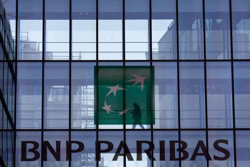 © Reuters. FILE PHOTO: A man is silhouetted as he walks behind the logo of BNP Paribas at the bank's building in Issy-les-Moulineaux, near Paris, France, February 3, 2022. REUTERS/Gonzalo Fuentes/File Photo