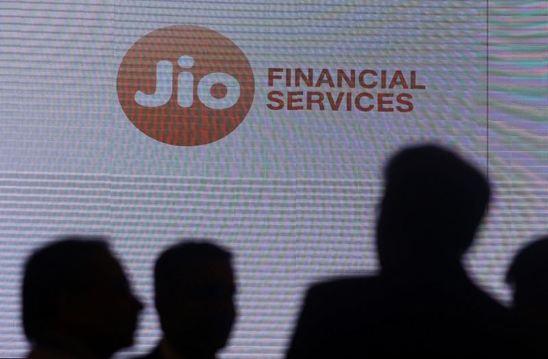 &copy; Reuters. FILE PHOTO: People stand next to a logo of Jio Financial Services ahead of its listing ceremony at the Bombay Stock Exchange in Mumbai, India, August 21, 2023. REUTERS/Francis Mascarenhas/File Photo