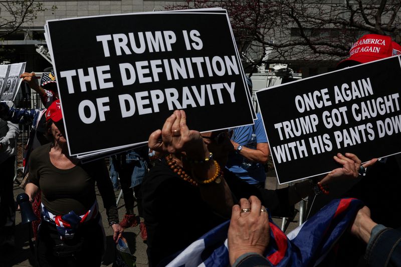 &copy; Reuters. An anti-Trump demonstrator holds banners next to pro-Trump demonstrators as people gather outside the courthouse, on the day of Republican presidential candidate and former U.S. President Donald Trump's hush money criminal trial, in New York City, U.S., A