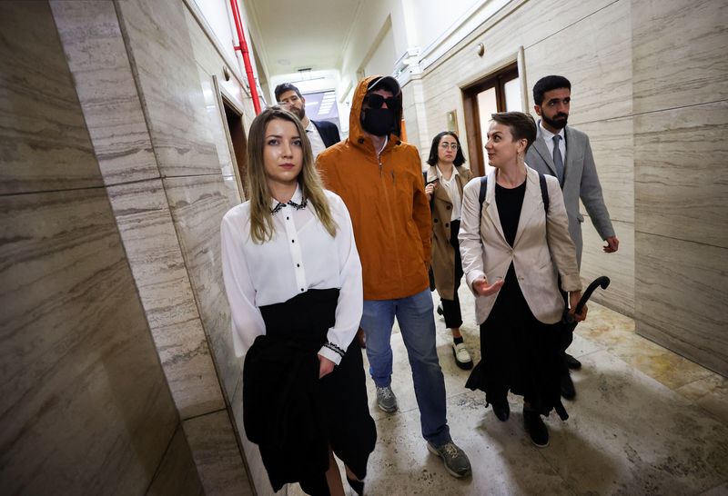 &copy; Reuters. A Ukrainian man who alleges he was tortured by Russian occupying forces walks with Ibrahim Olabi, Chief Legal Counsel of the NGO The Reckoning Project, Tsvetelina van Benthem, a University of Oxford legal scholar and Senior Legal Advisor at The Reckoning