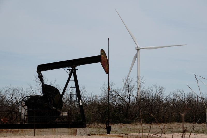 &copy; Reuters. FOTO DE ARCHIVO: Un balancín petrolero perfora crudo del yacimiento de Yates, en la cuenca del Pérmico, al oeste de Texas, mientras se ve a lo lejos un aerogenerador GE de 1,5 MW del parque eólico Desert Sky, cerca de Iraan, Texas, Estados Unidos. 17 d
