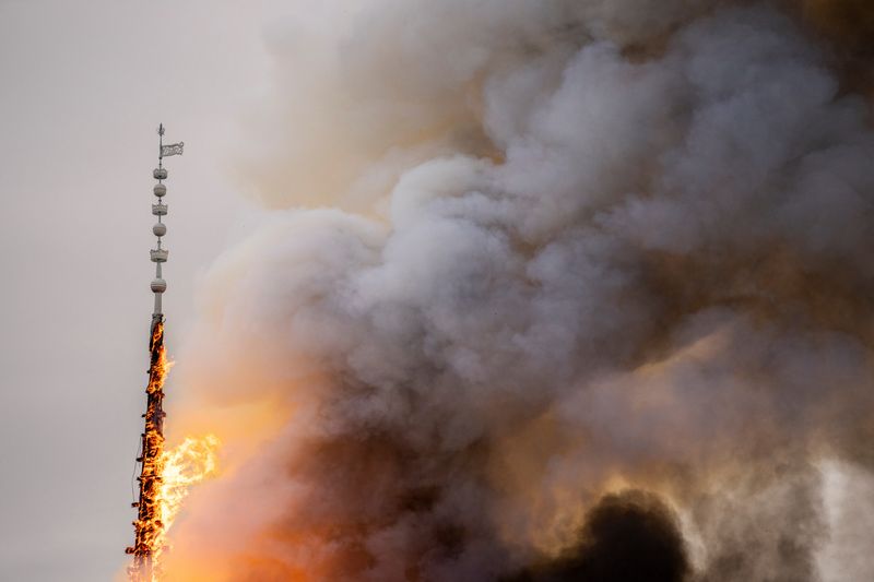 &copy; Reuters. ４月１６日、北欧デンマークの首都コペンハーゲンで、街のシンボルとされる歴史的建造物の旧証券取引所で火災が発生し、屋根の上の尖塔（せんとう）が焼け落ちた。提供写真（２０２４