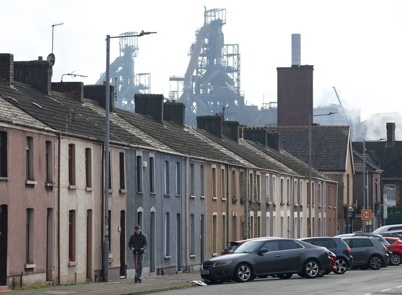 &copy; Reuters. File photo: A person rides a scooter along a residential street with Tata Steel Port Talbot steel production plant seen behind, ahead of its planned transition from blast furnace to electric arc furnaces, at Port Talbot, Wales, Britain, March 11, 2024. RE