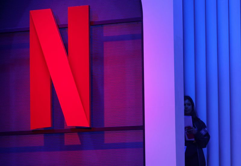 © Reuters. FILE PHOTO: A woman stands next to a logo of Netflix during an event in Mumbai, India, February 29, 2024. REUTERS/Francis Mascarenhas/File Photo