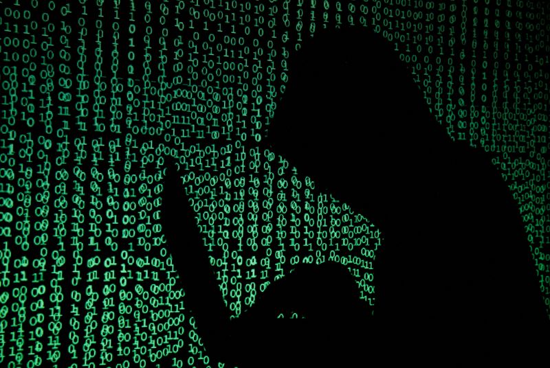 © Reuters. FILE PHOTO: A hooded man holds a laptop computer as cyber code is projected on him in this illustration picture taken on May 13, 2017. REUTERS/Kacper Pempel/Illustration/File Photo