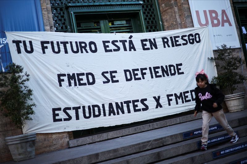 &copy; Reuters. A girl plays in front of a banner that reads "Your future is at risk. The Medical University is defended" outside the University of Buenos Aires Medical School, in the run-up to a national strike on April 23 against Argentina's President Javier Milei's po