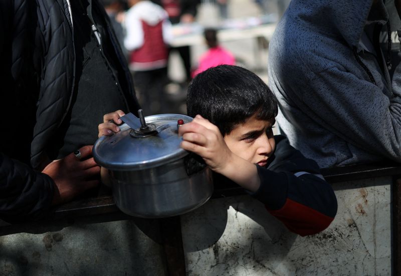 &copy; Reuters. A Palestinian child waits to receive food cooked by a charity kitchen amid shortages of food supplies, as the ongoing conflict between Israel and the Palestinian Islamist group Hamas continues, in Rafah, in the southern Gaza Strip, February 5, 2024. REUTE