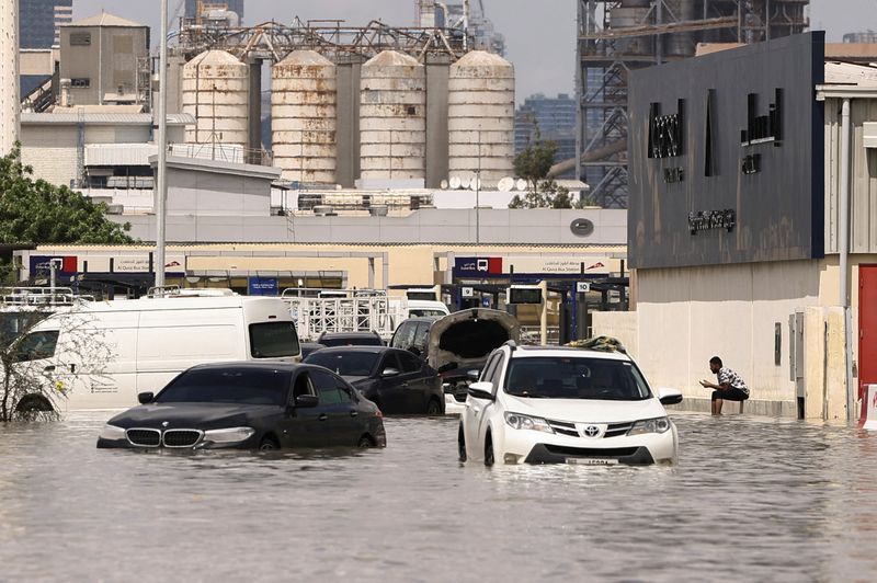 &copy; Reuters. Una persona se sienta cerca de vehículos varados en las aguas de las inundaciones causadas por las fuertes lluvias en Dubái, Emiratos Árabes Unidos. 17 de abril de 2024. REUTERS/Amr Alfiky