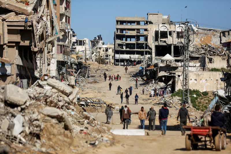 &copy; Reuters. فلسطينيون يسيرون بالقرب من أنقاض المنازل التي دمرت خلال الهجوم العسكري الإسرائيلي، وسط الصراع المستمر بين إسرائيل وحماسفي غزة يوم 20 مارس آ