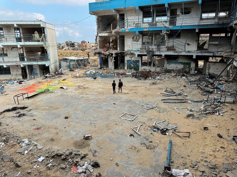 &copy; Reuters. Gli scolari palestinesi Abed Al-Qara e Muhammad Al-Fajem ispezionano la loro scuola distrutta durante l'offensiva militare israeliana, nell'ambito del conflitto in corso tra Israele e Hamas, a Khan Younis, nel sud della Striscia di Gaza, il 14 aprile 2024