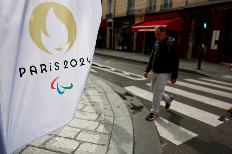 &copy; Reuters. A man walks near a flag with the logo of the Paris 2024 Olympic and Paralympic Games in Paris, France, March 25, 2024. REUTERS/Gonzalo Fuentes/ File photo