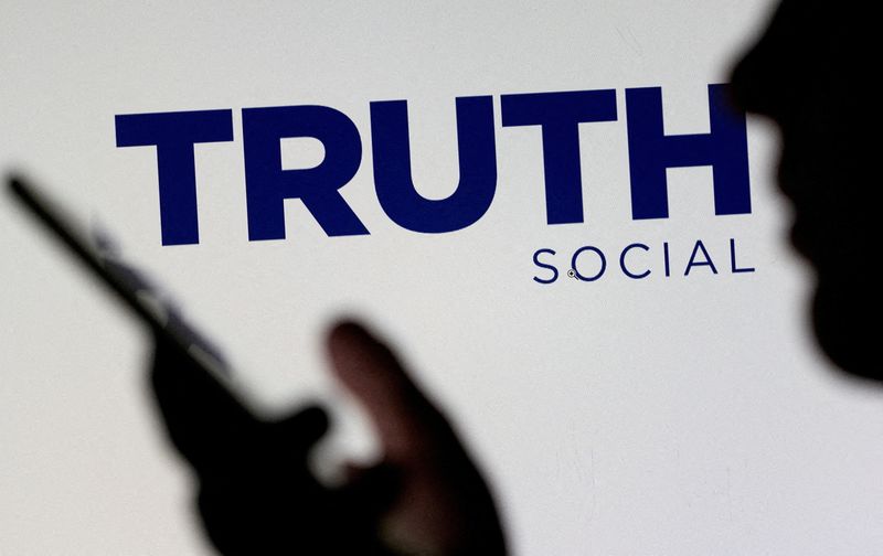 © Reuters. FILE PHOTO: The Truth social network logo is seen displayed behind a woman holding a smartphone in this picture illustration taken February 21, 2022. REUTERS/Dado Ruvic/Illustration/File Photo