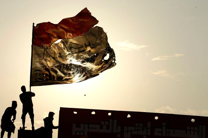 &copy; Reuters. Des personnes brandissent le drapeau irakien lors d'une manifstation anti-gouvernementale, à Bagdad. /Photo prise le 10 décembre 2019/REUTERS/Alaa al-Marjani