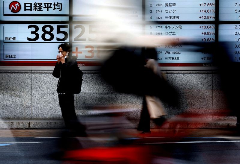 &copy; Reuters. Passersby walk past electronic screens displaying Japan's Nikkei share average outside a brokerage in Tokyo, Japan February 19, 2024. REUTERS/Issei Kato/File Photo