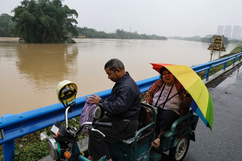 &copy; Reuters. Residentes montan en una motoneta cerca de un río desbordado, tras las fuertes lluvias en Qingyuan, provincia de Cantón, China. 22 de abril de 2024. REUTERS/Tingshu Wang