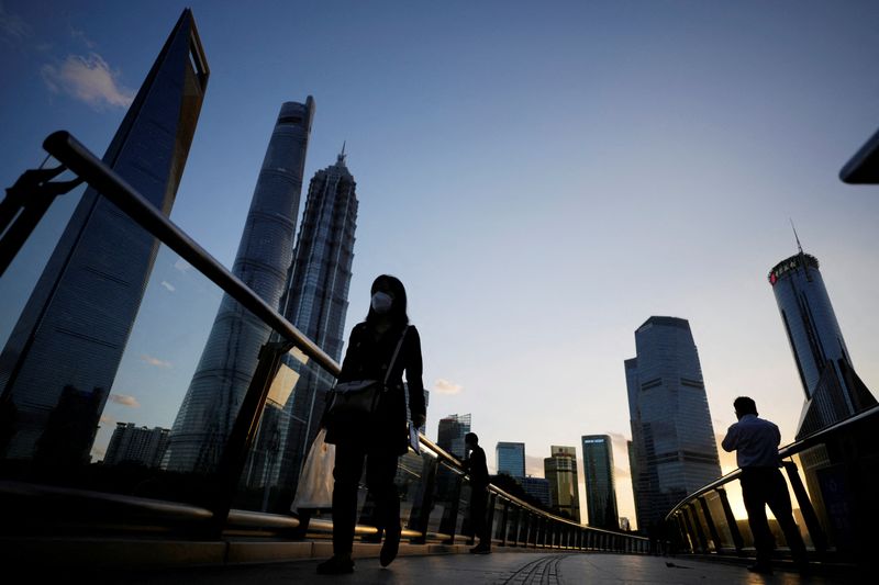 © Reuters. FILE PHOTO: People walk on an overpass past office towers in the Lujiazui financial district of Shanghai, China October 17, 2022. REUTERS/Aly Song/File Photo