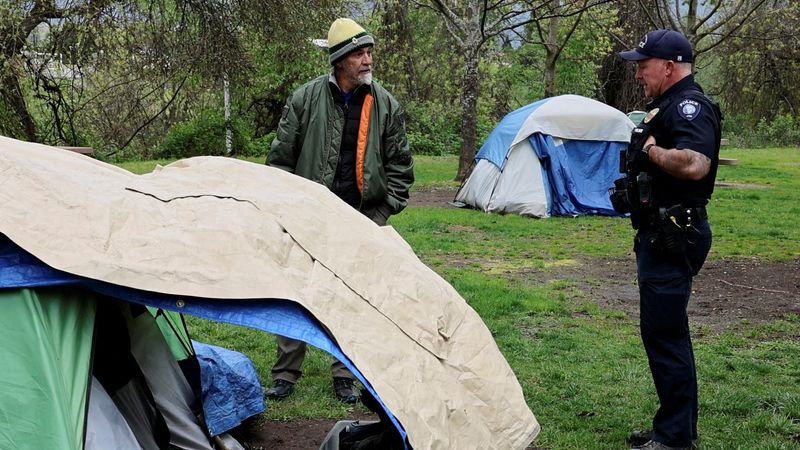 &copy; Reuters. FILE PHOTO: An officer tells an unhoused man that he needs to leave the park in two hours, in Grants Pass, Oregon, U.S., April 18, 2024. REUTERS/Deborah Bloom/File Photo