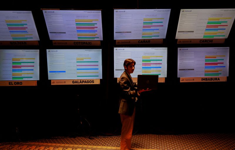 &copy; Reuters. FILE PHOTO: A journalist looks at his laptop in front of a screen displaying preliminary results of a referendum on security measures to fight rising violence, at the Command Center of the National Electoral Council in Quito, Ecuador April 21, 2024. REUTE