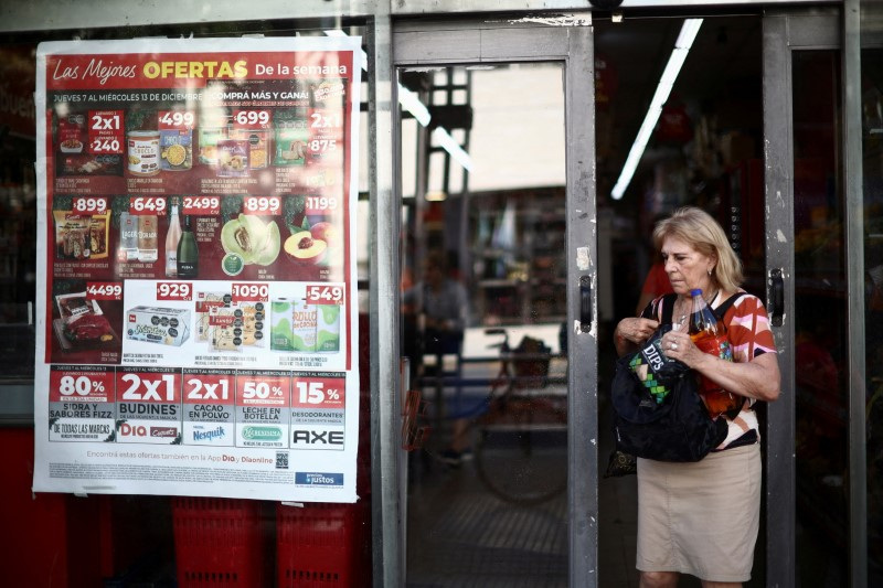 &copy; Reuters. FILE PHOTO: A woman exits a supermarket displaying prices for different products on it's window in Buenos Aires, Argentina, December 12, 2023. REUTERS/Tomas Cuesta/File Photo