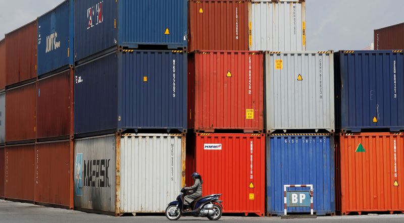 &copy; Reuters. FILE PHOTO: A woman rides a motorcycle as she passes containers at Hai Phong port, Vietnam September 25, 2018. Picture taken September 25, 2018. REUTERS/Kham/File Photo