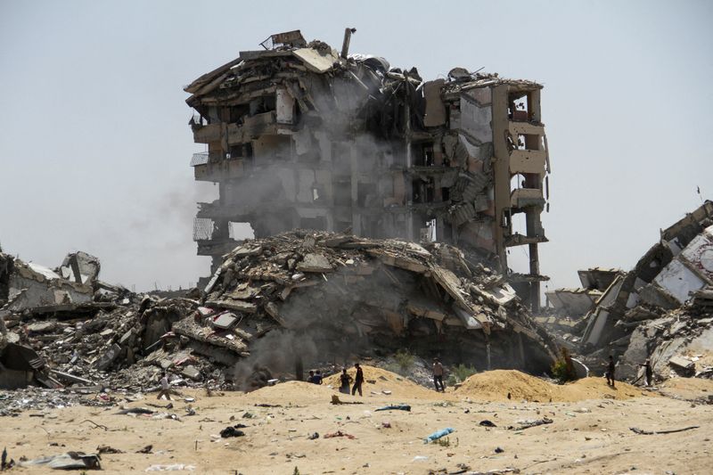&copy; Reuters. فلسطينيون يسيرون بجوار أنقاض مبان سكنية دمرها قصف إسرائيلي في شمال قطاع غزة يوم 22 أبريل نيسان 2024. تصوير: محمود عيسى - رويترز