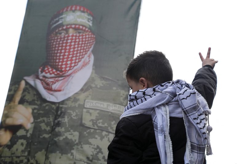 &copy; Reuters. طفل يقف بجوار صورة للمتحدث باسم كتائب عز الدين القسام، الجناح العسكري لحركة المقاومة الإسلامية (حماس) أبو عبيدة في عمان بالأردن يوم 15 مارس آ