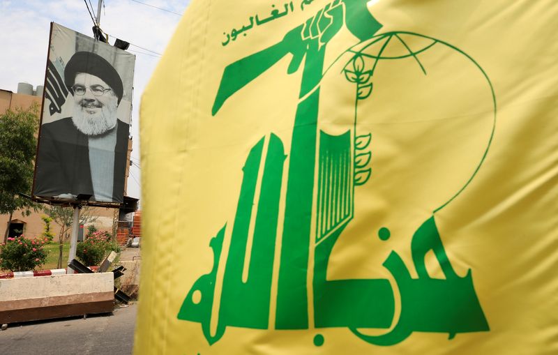 © Reuters. علم جماعة حزب الله إلى جانب صورة لزعيم الحركة حسن نصر الله في صورة من أرشيف رويترز 