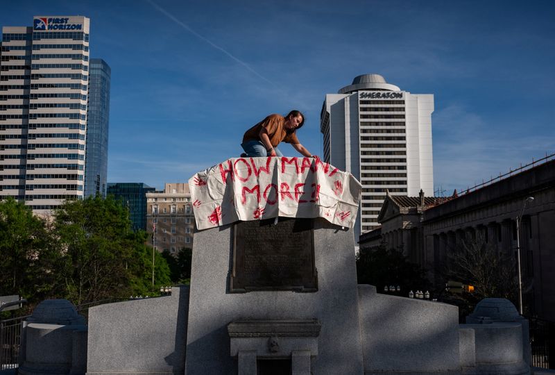 &copy; Reuters. A gun reform activists hangs a body bag on the granite base of the former Edward W. Carmack statue which was destroyed in 2020 at the Tennessee State Capitol building, following the House vote to adopt Senate Bill 1325 which would authorize teachers, prin