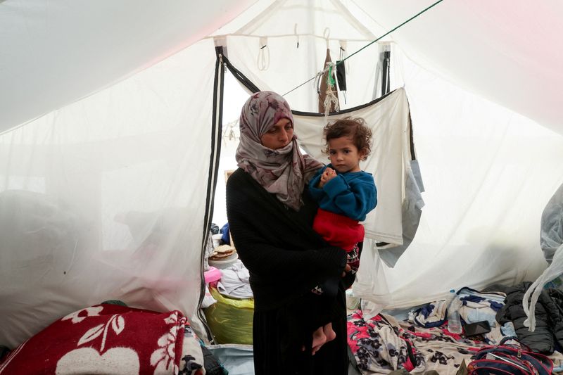 &copy; Reuters. FILE PHOTO: Displaced Palestinian woman Hana Tabash holds her daughter after she was checked for malnutrition, at their tent in Rafah, in the southern Gaza Strip, February 14, 2024. REUTERS/Ibraheem Abu Mustafa/File Photo