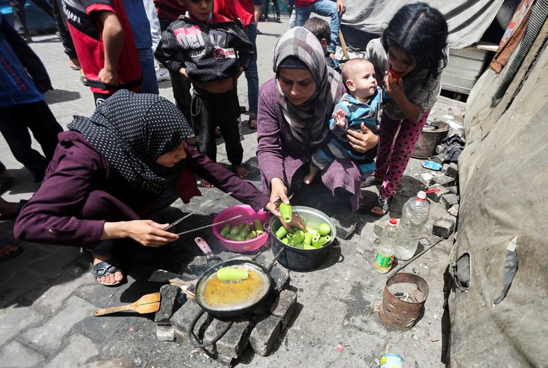 &copy; Reuters. FOTO DE ARCHIVO: Palestinos desplazados, que huyeron de sus hogares debido a los ataques israelíes, cocinan mientras se refugian en una escuela afiliada a la UNRWA, en medio del conflicto en curso entre Israel y Hamás, en Deir Al-Balah, en el centro de 