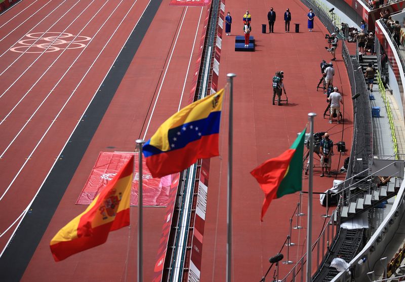 © Reuters. FOTO DE ARCHIVO: Imagen referencial de las banderas de Venezuela, Portugal y España se izan durante la ceremonia con los atletas en el podio al fondo en el Triple Salto Femenino de los Juegos Olímpicos de Tokio 2020 en el Estadio Olímpico de Tokio, Japón. 2 de agosto, 2021. REUTERS/Hannah Mckay/Archivo