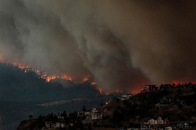 &copy; Reuters. Foto de Archivo: Humo y llamas de incendios forestales de fondo para las casas al otro lado del lago Okanagan en West Kelowna, Columbia Británica, Canadá. 17 de agosto de 2023. REUTERS/Dan Riedlhuber.