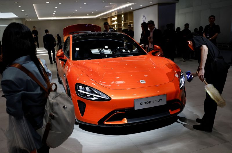 © Reuters. A staff member cleans a Xiaomi SU7 electric vehicle displayed at the Beijing International Automotive Exhibition, or Auto China 2024, in Beijing, China, April 25, 2024. REUTERS/Tingshu Wang