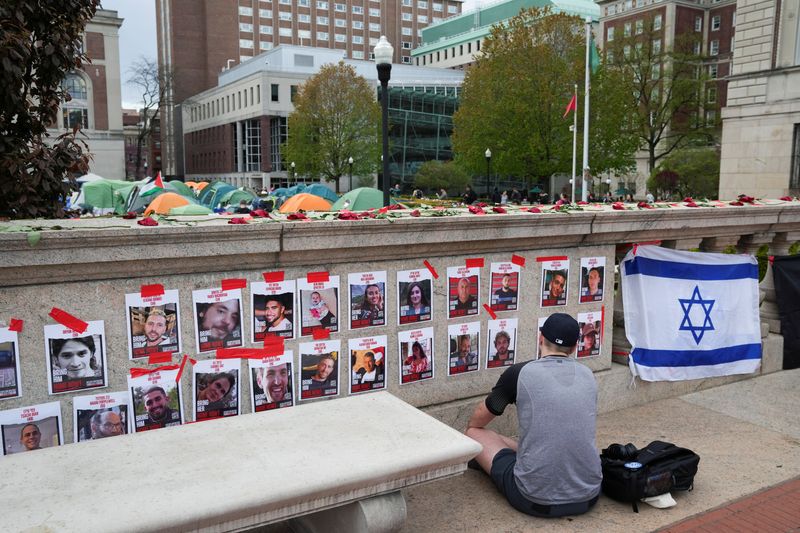 &copy; Reuters. A person prays in front of photos of hostages posted on campus near an encampment where students are protesting in support of Palestinians at Columbia University, during the ongoing conflict between Israel and the Palestinian Islamist group Hamas, in New 