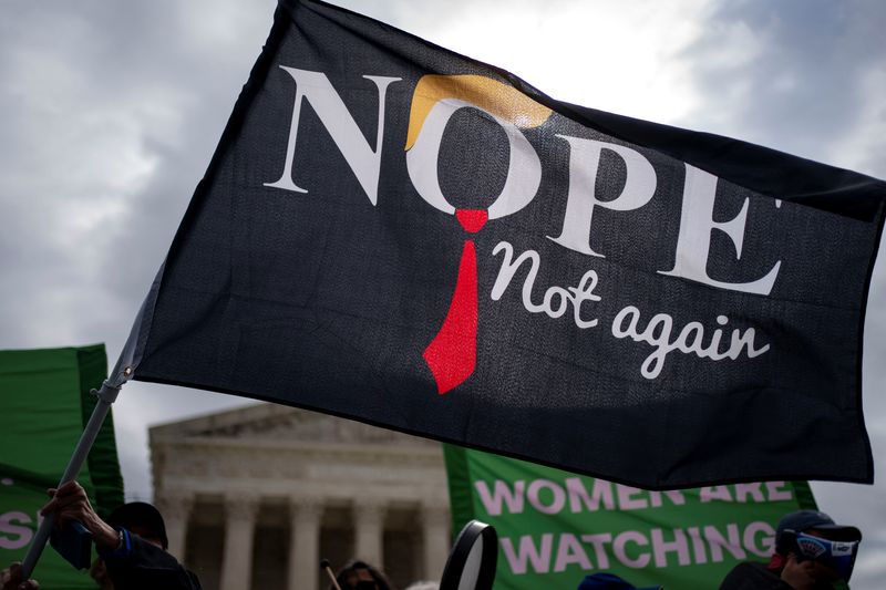 © Reuters. A person waves a flag while Women’s March activists hold a “Feminists vs. Fascists” demonstration as the Supreme Court Justices hear arguments on former President Trump’s claim of presidential immunity over criminal charges over his efforts to overturn the 2020 presidential election results outside the U.S. Supreme Court in Washington, U.S., April 25, 2024. REUTERS/Bonnie Cash
