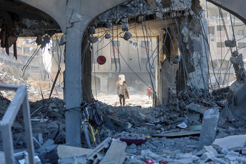 &copy; Reuters. FOTO DE ARCHIVO: Un hombre palestino lleva sus pertenencias mientras camina entre los escombros de un edificio residencial destruido tras una incursión israelí, en la ciudad de Hamad, en el sur de la Franja de Gaza. 13 de marzo de 2024. REUTERS/Ahmed Za