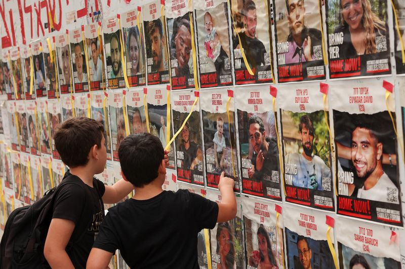 &copy; Reuters. طفلان ينظران إلى ملصقات مطبوع عليها صور المحتجزين لدى حركة المقاومة الإسلامية (حماس) في تل أبيب يوم 26 أبريل نيسان 2024. تصوير: شانون ستيبلتون - 