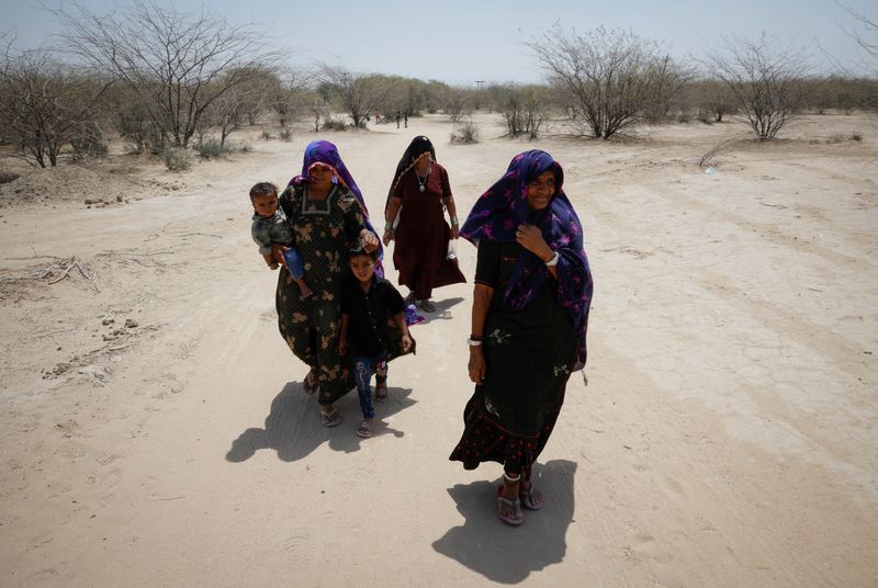 © Reuters. Women walk through a desert area towards their home after casting their vote at a polling station during the second phase of the general elections, in Barmer, Rajasthan, India, April 26, 2024. REUTERS/Adnan Abidi