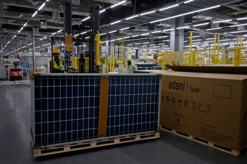 © Reuters. FILE PHOTO: A worker shifts Photovoltaic Modules for packing at the plant of Adani Green Energy Ltd (AGEL), in Mundra, India, April 11, 2024. REUTERS/Amit Dave/File Photo