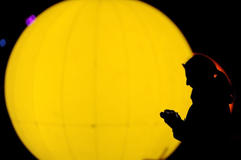 © Reuters. FILE PHOTO: A woman looks on her mobile phone in front of an illuminated object during in Berlin, Germany November 18, 2016. REUTERS/Stefanie Loos/file photo