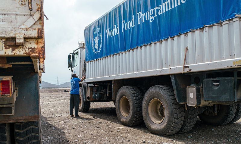 © Reuters. FILE PHOTO: A WFP worker stands next to a truck carrying aid from Port Sudan to Sudan, in Sudan November 12, 2024. WFP/Abubakar Garelnabei/Handout via REUTERS/File Photo