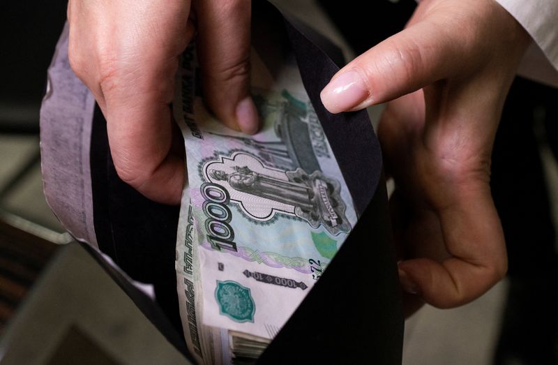 © Reuters. FILE PHOTO: An employee holds an envelope with Russian 1000-rouble banknotes in a bank office in Moscow, Russia, in this illustration picture taken October 9, 2023. REUTERS/Maxim Shemetov/Illustration/File Photo