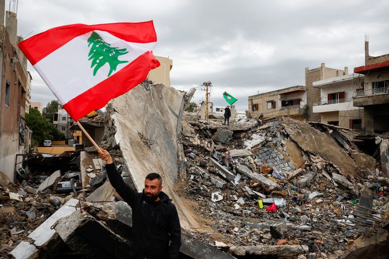 &copy; Reuters. Homem com bandeira do Líbano em meio a destroços em Tiron 27/11/2024   REUTERS/Adnan Abidi