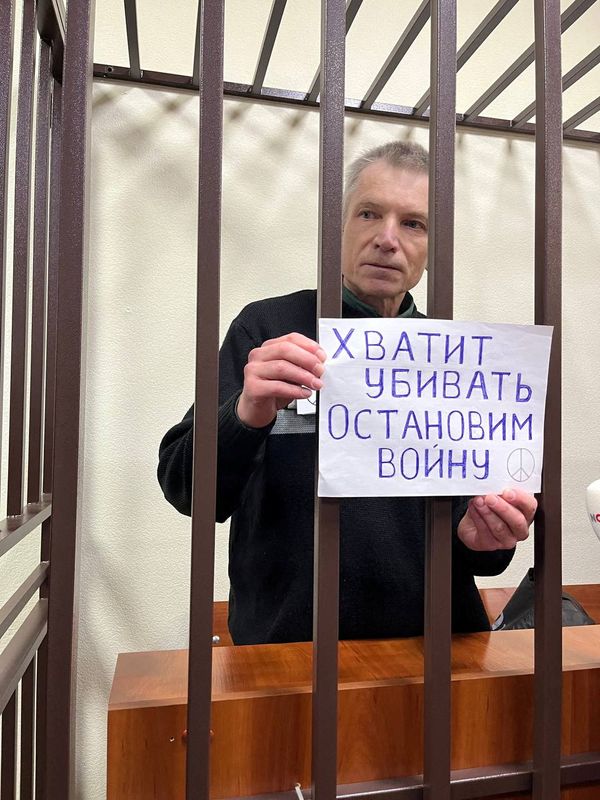 &copy; Reuters. Moscow city councillor Alexei Gorinov, serving a seven-year sentence for criticising Russia's invasion of Ukraine, holds a placard reading "Stop killing. Let's stop the war" as he stands inside a defendants' cage during a new court hearing against him for