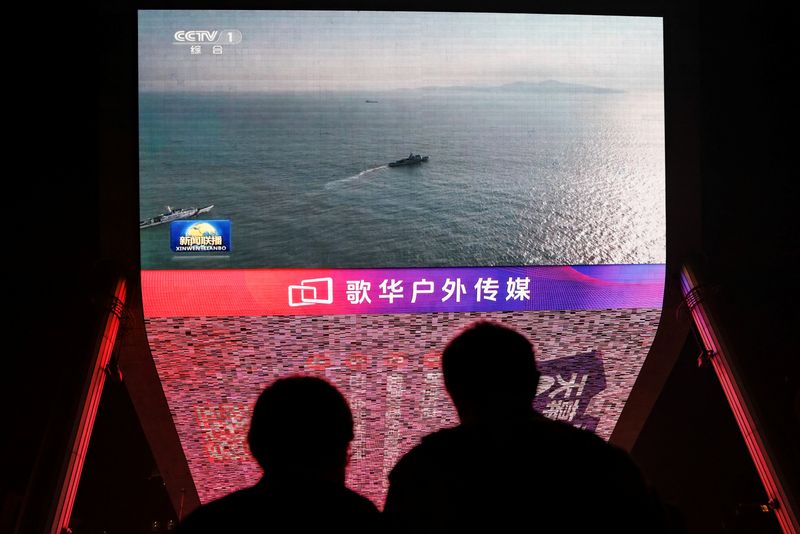 © Reuters. FILE PHOTO: People look at a giant screen showing news footage of military drills conducted in the Taiwan Strait and areas to the north, south and east of Taiwan, by the Eastern Theatre Command of the Chinese People's Liberation Army (PLA), in Beijing, China October 14, 2024. REUTERS/Tingshu Wang/File Photo