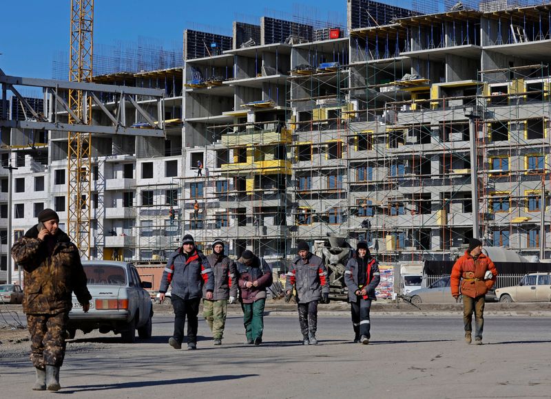 &copy; Reuters. FILE PHOTO: Workers walk in front of an apartment building under construction, in the course of Russia-Ukraine conflict in Mariupol, Russian-controlled Ukraine, February 10, 2023. REUTERS/Alexander Ermochenko/File Photo