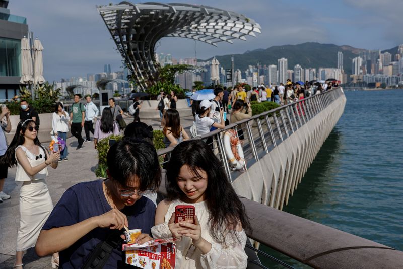 © Reuters. FILE PHOTO: Mainland Chinese tourists walk in front of the skyline of buildings at Tsim Sha Tsui, in Hong Kong, China May 2, 2023. REUTERS/Tyrone Siu/File Photo